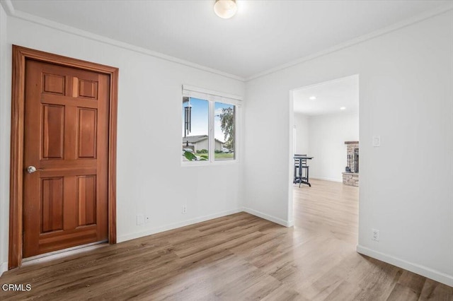 spare room featuring crown molding, wood finished floors, and baseboards