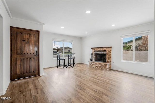 living room featuring baseboards, ornamental molding, a fireplace, and wood finished floors