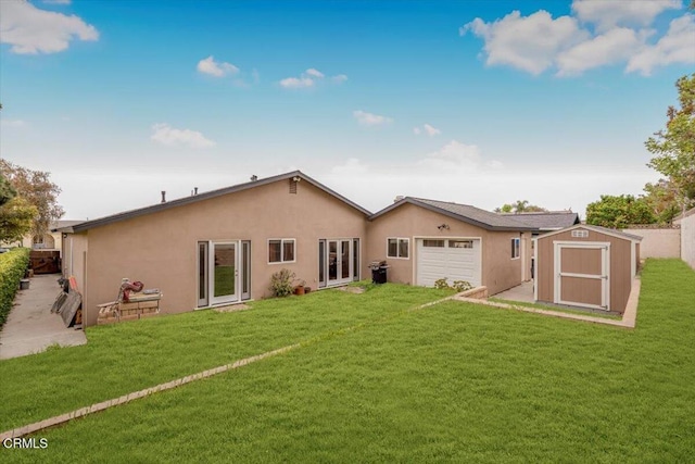 back of property featuring a storage shed, an attached garage, a yard, stucco siding, and an outbuilding