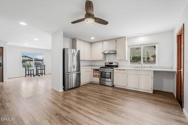 kitchen with light countertops, stainless steel appliances, light wood-style flooring, and a sink