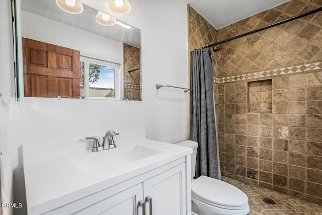 bathroom with vanity, toilet, and tiled shower
