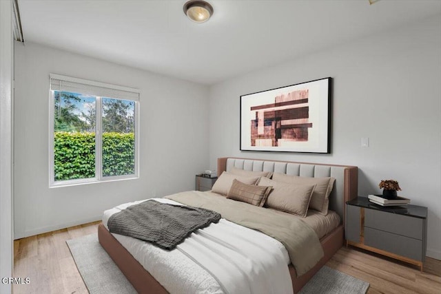 bedroom featuring light wood finished floors and baseboards
