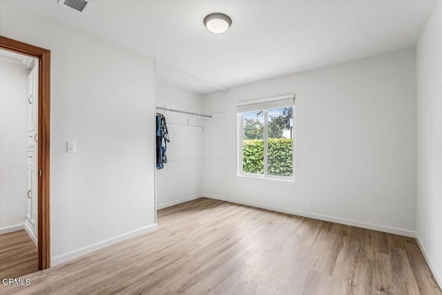 unfurnished bedroom with baseboards, a closet, visible vents, and wood finished floors