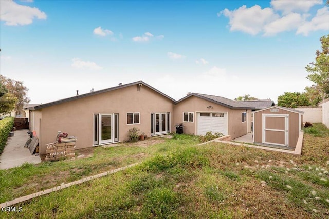 back of house with a garage, a storage unit, stucco siding, fence, and an outbuilding