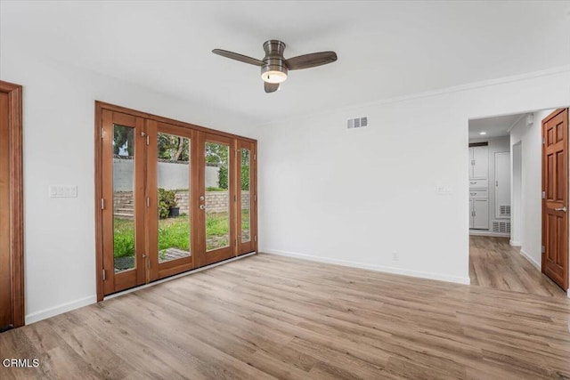 empty room featuring light wood finished floors, visible vents, and baseboards