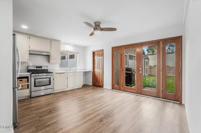 kitchen with light countertops, stainless steel appliances, light wood-type flooring, and a sink