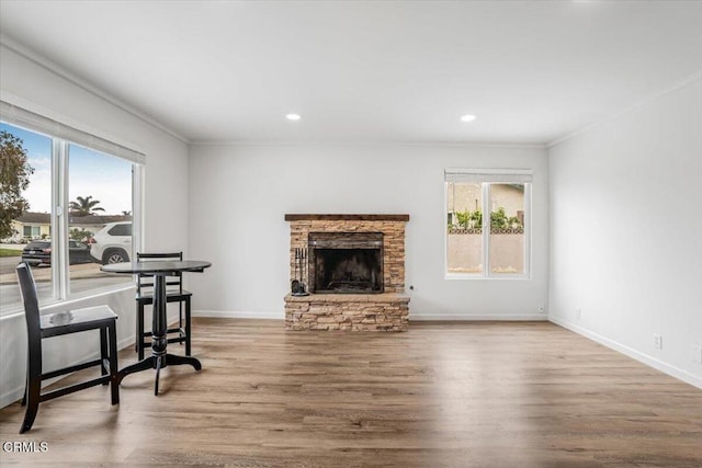 living area featuring wood finished floors, a fireplace, baseboards, ornamental molding, and recessed lighting
