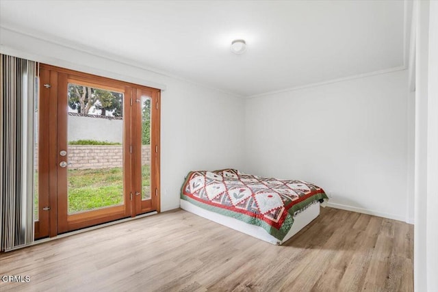 bedroom featuring crown molding, baseboards, wood finished floors, and access to exterior