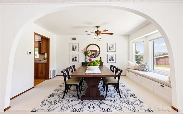 dining room featuring arched walkways, ceiling fan, visible vents, and light colored carpet