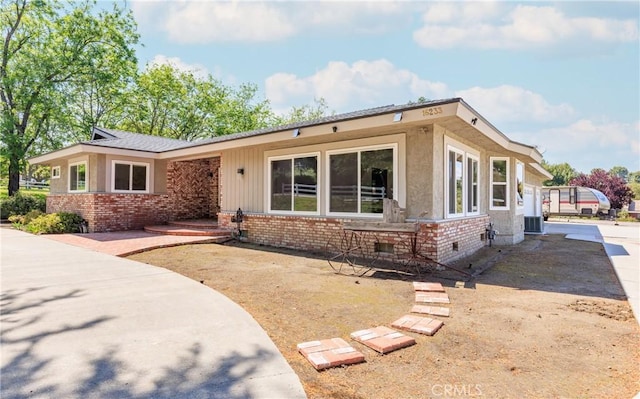 view of front of home with crawl space, brick siding, and central AC
