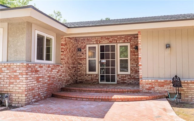 entrance to property with a porch and brick siding
