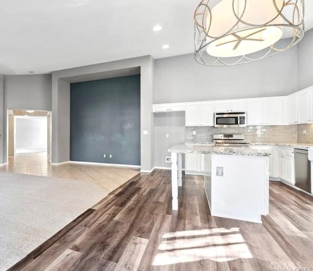 25624 Driftview Cir, Menifee, CA 92584 - kitchen with stainless steel appliances, a center island, light stone countertops, white cabinets, and decorative backsplash