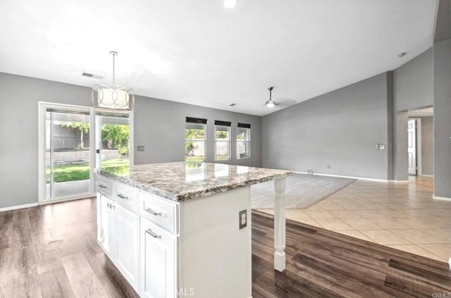 25624 Driftview Cir, Menifee, CA 92584 - kitchen with open floor plan, white cabinets, light stone counters, vaulted ceiling, and a kitchen island