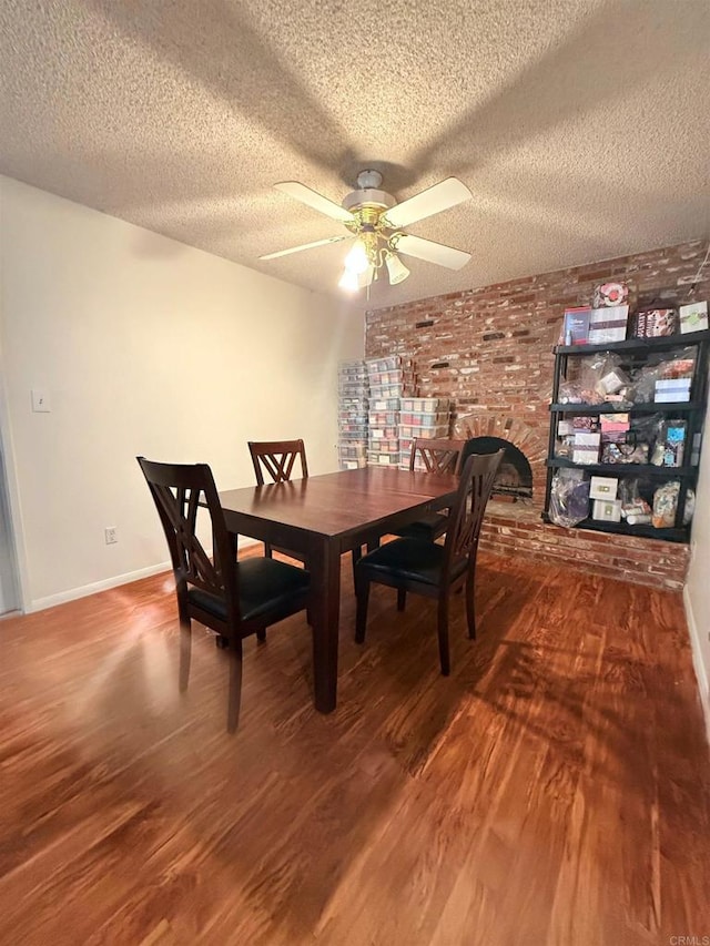 dining room with brick wall, ceiling fan, a textured ceiling, and wood finished floors