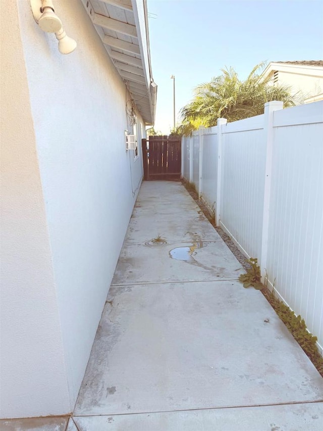 view of side of home featuring stucco siding and fence