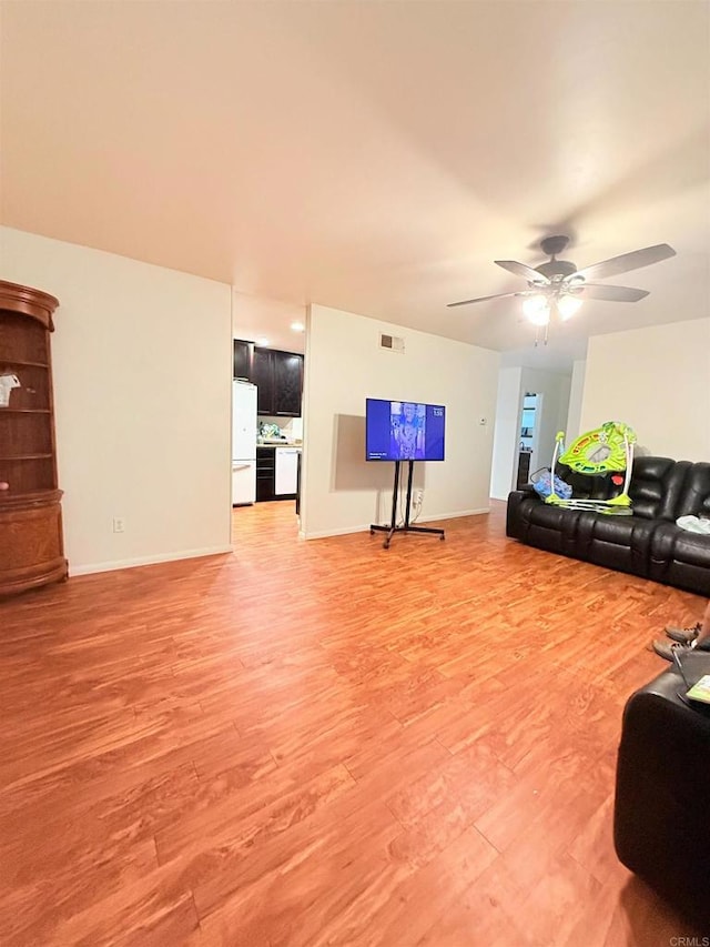 living area with light wood finished floors, baseboards, ceiling fan, and visible vents