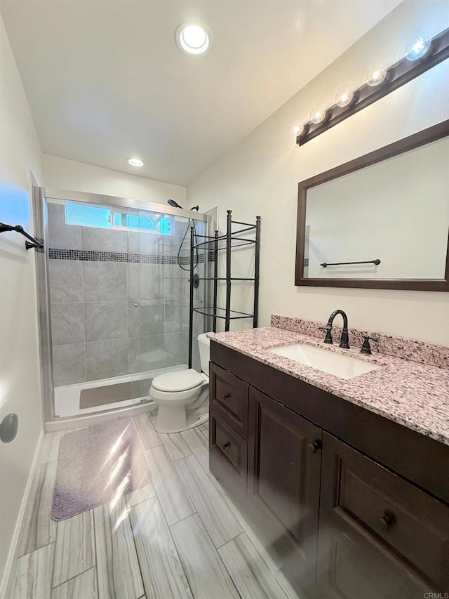 bathroom with toilet, a stall shower, baseboards, vanity, and recessed lighting