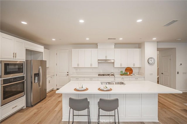 12931 Lotus St, Garden Grove, CA 92840 - kitchen with a sink, stainless steel appliances, light wood-type flooring, a breakfast bar area, and under cabinet range hood