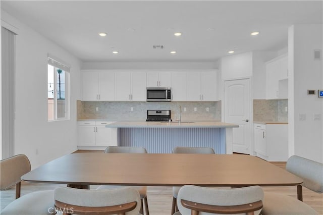 14667 Gulfstream Ln, Moreno Valley, CA 92553 - kitchen featuring white cabinetry, backsplash, a kitchen island with sink, and appliances with stainless steel finishes