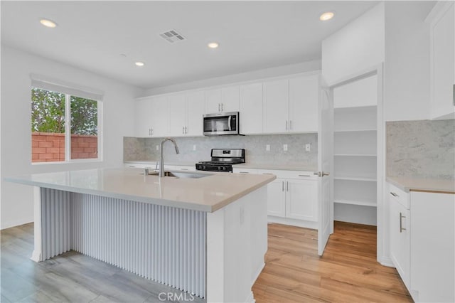 14667 Gulfstream Ln, Moreno Valley, CA 92553 - kitchen with appliances with stainless steel finishes, visible vents, a sink, a center island with sink, and light wood-type flooring