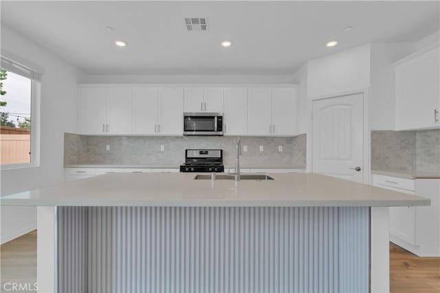 14667 Gulfstream Ln, Moreno Valley, CA 92553 - kitchen with stainless steel appliances, light wood-type flooring, a sink, light countertops, and an island with sink