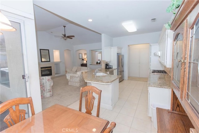 1490 N Dewitt Ave, Clovis, CA 93619 - dining space with light tile patterned flooring, visible vents, arched walkways, a ceiling fan, and a glass covered fireplace