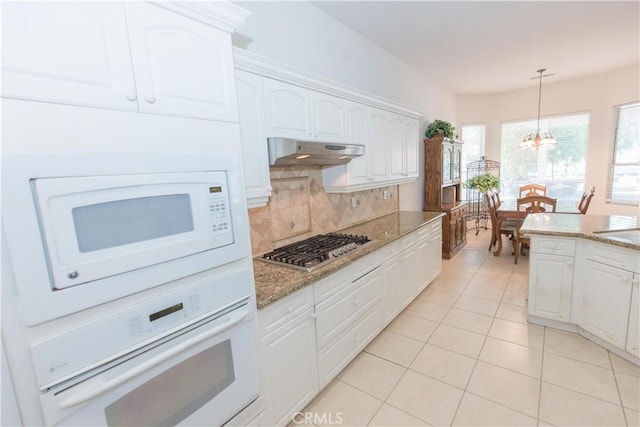 1490 N Dewitt Ave, Clovis, CA 93619 - kitchen featuring under cabinet range hood, decorative backsplash, light stone countertops, and white appliances