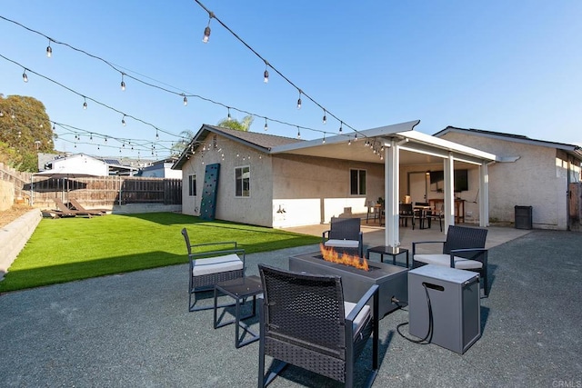 rear view of property featuring an outdoor fire pit, stucco siding, a lawn, a fenced backyard, and a patio area