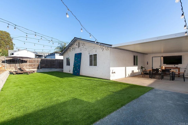 back of property featuring a yard, stucco siding, a patio area, and a fenced backyard