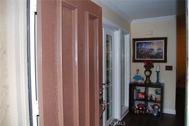 foyer with wood finished floors, baseboards, and ornamental molding