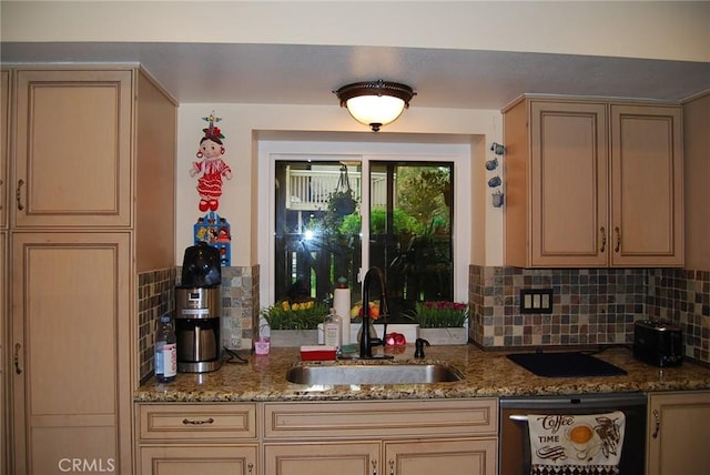 kitchen featuring stone countertops, dishwashing machine, decorative backsplash, and a sink