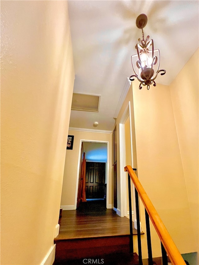 stairway with a chandelier, crown molding, baseboards, and wood finished floors