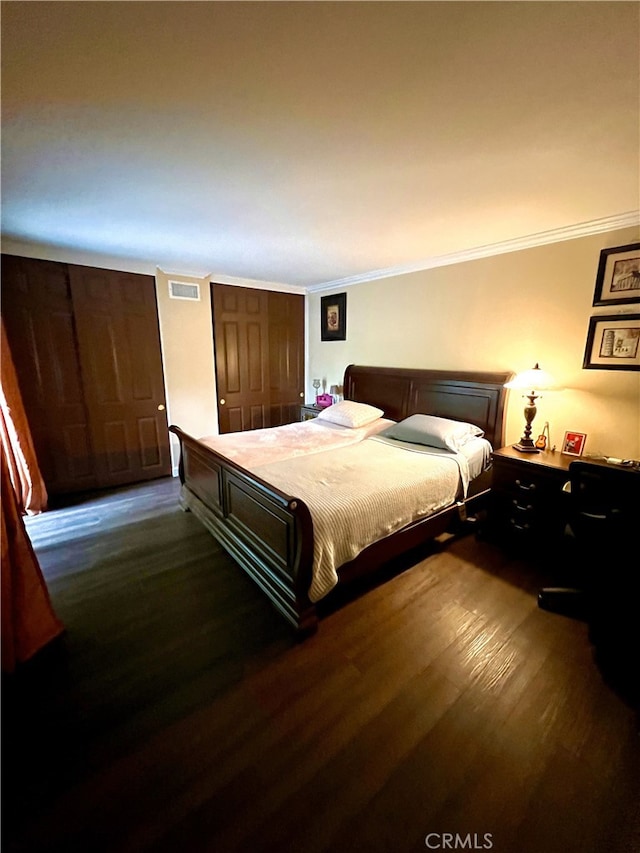 bedroom featuring dark wood-style flooring, a closet, visible vents, and crown molding