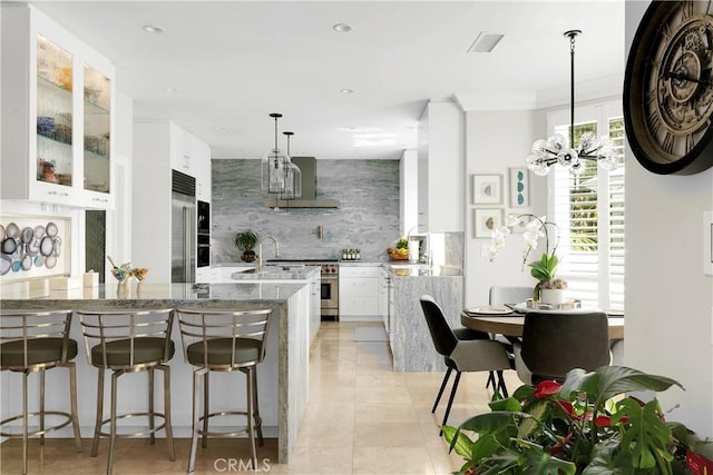 184 Halsbury Ct, Lake Sherwood, CA 91361 - kitchen with a kitchen bar, white cabinetry, high quality appliances, wall chimney exhaust hood, and decorative backsplash