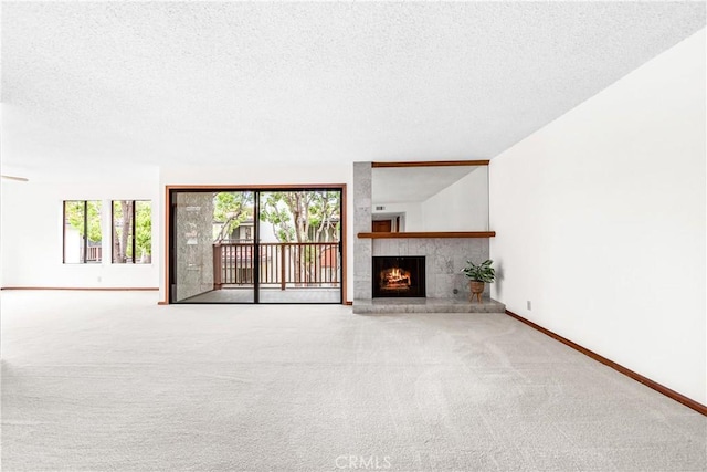 unfurnished living room featuring a textured ceiling, carpet, baseboards, and a wealth of natural light