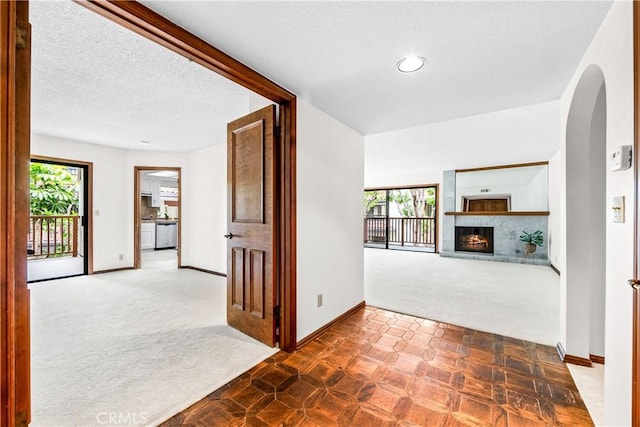interior space featuring carpet, baseboards, arched walkways, and a healthy amount of sunlight