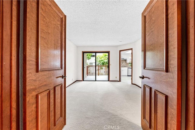 interior space featuring light colored carpet, a textured ceiling, and baseboards