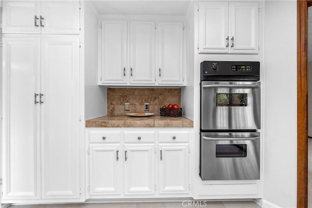 kitchen featuring white cabinetry, double oven, and tasteful backsplash