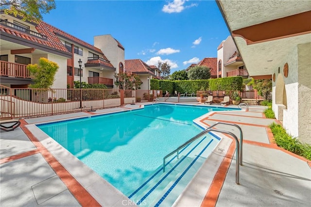 pool featuring fence, a patio area, and a residential view