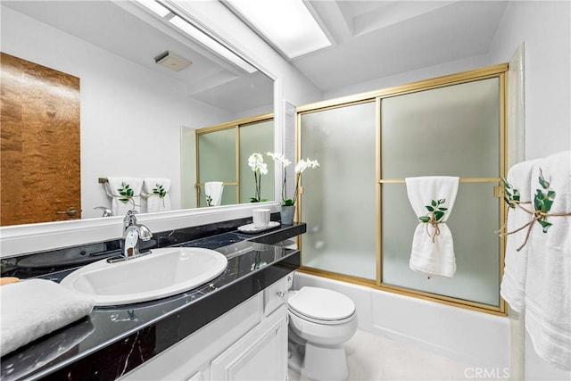 bathroom with vanity, toilet, and bath / shower combo with glass door