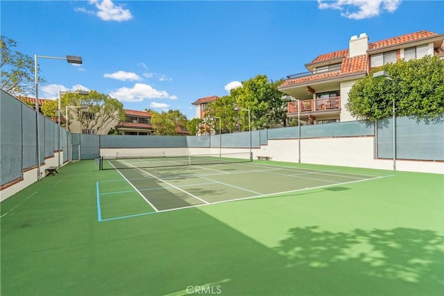 view of tennis court with community basketball court and fence