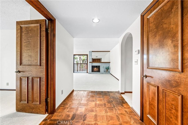hall with tile patterned floors, baseboards, arched walkways, and recessed lighting