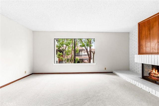 unfurnished living room with a fireplace, a textured ceiling, carpet, and baseboards