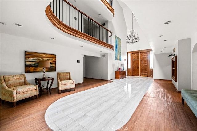 foyer featuring a chandelier, a towering ceiling, baseboards, and light wood-type flooring