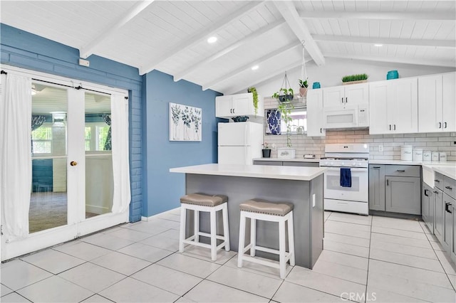 10541 Cliota St, Whittier, CA 90601 - kitchen featuring white appliances, gray cabinets, a kitchen island, tasteful backsplash, and a kitchen bar