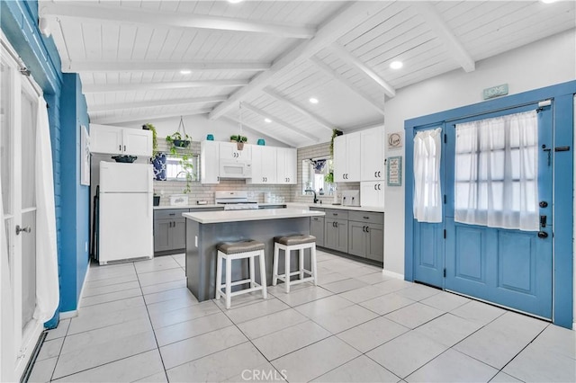 10541 Cliota St, Whittier, CA 90601 - kitchen with white appliances, gray cabinets, decorative backsplash, a kitchen bar, and a center island