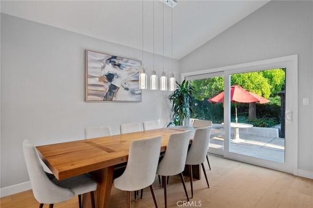 dining space with lofted ceiling, baseboards, and light wood-style flooring