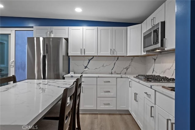 kitchen featuring light stone countertops, stainless steel appliances, and white cabinets