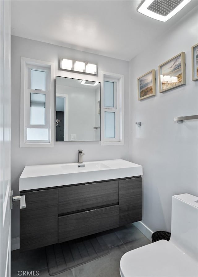 bathroom featuring baseboards, vanity, and toilet