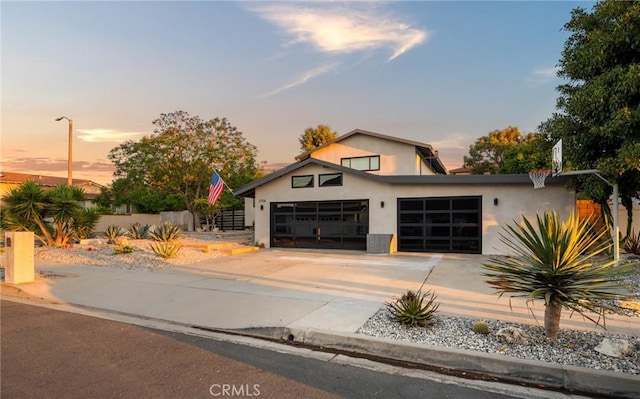 contemporary home featuring driveway, stucco siding, a garage, and fence